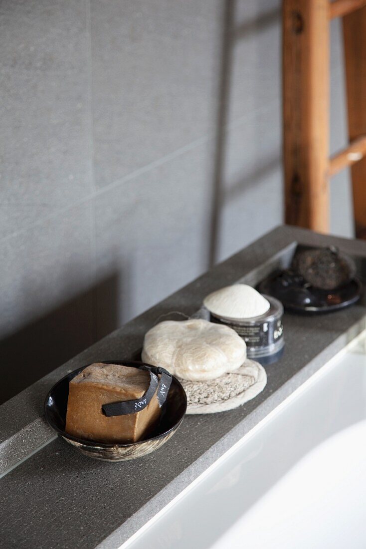 Various soaps on grey stone bathtub surround