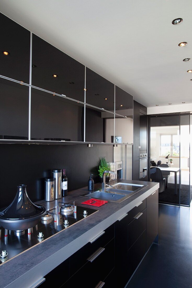 Modern kitchen counter with black doors in open-plan kitchen area with recessed spotlights in suspended ceiling