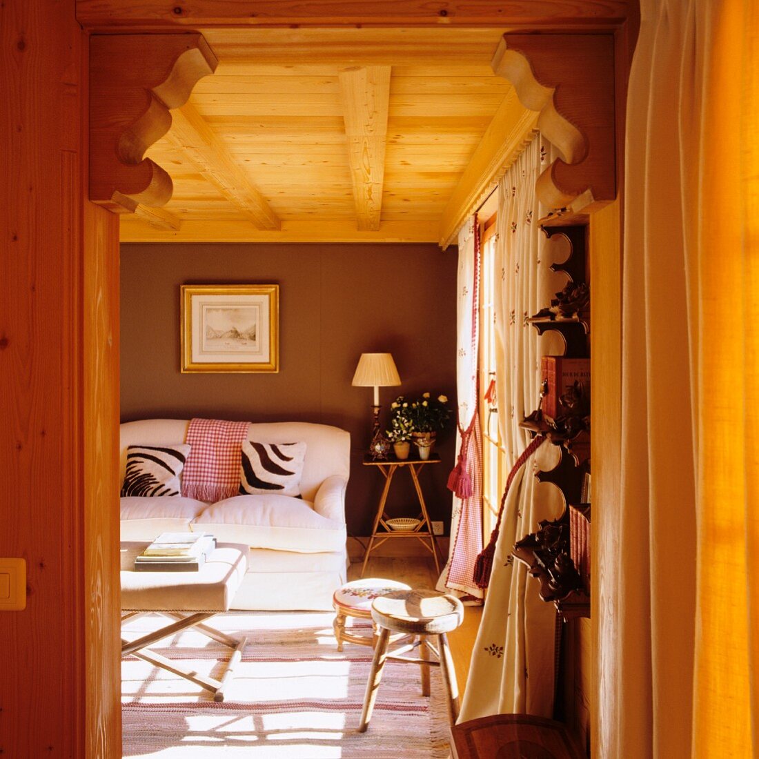Blick auf weisses Polstersofa und Kissen im Zebralook im Wohnzimmer eines Holzhauses
