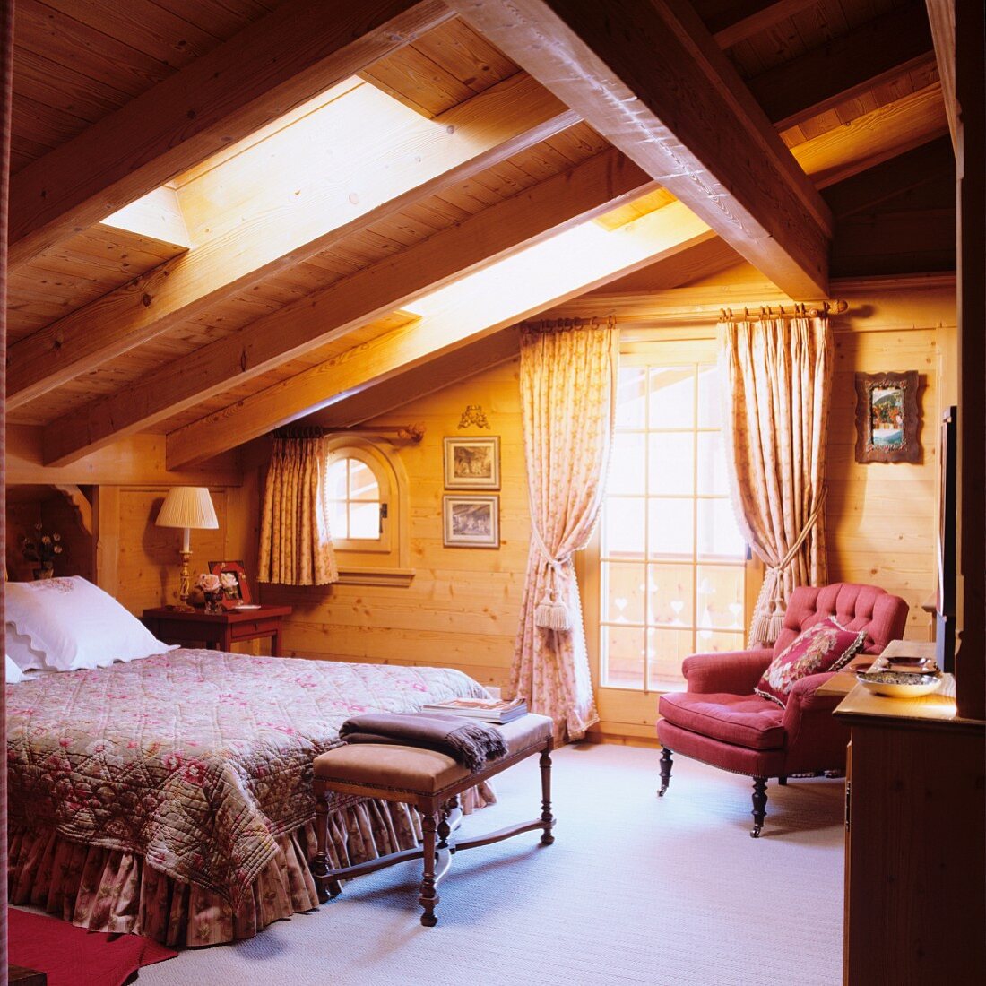Doppelbett unter Dachflächenfenster, gegenüber antiker Sessel neben Balkontür in Holzhaus