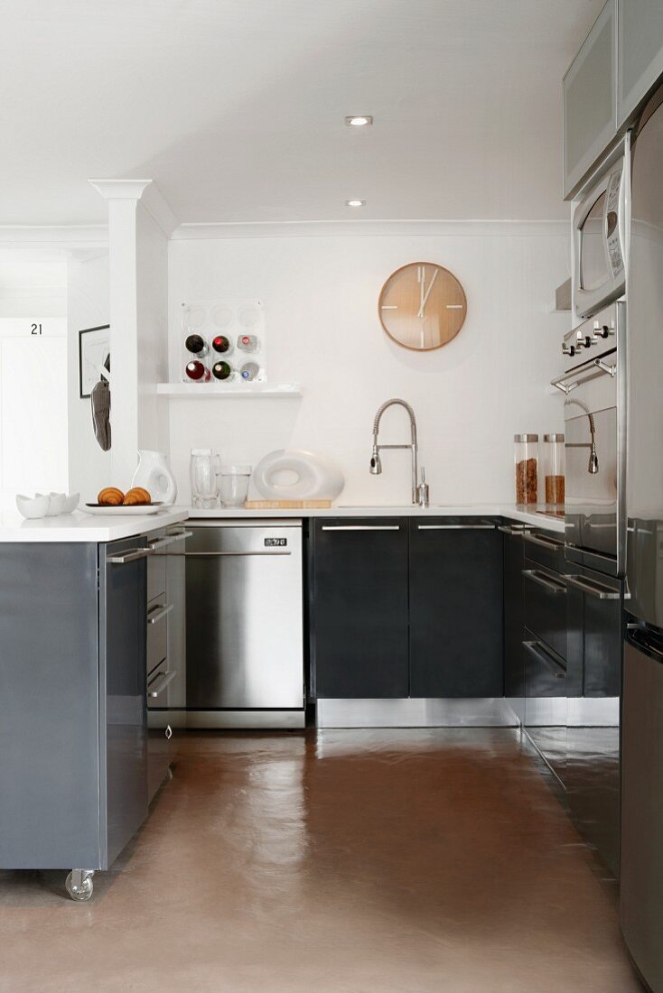 Open-plan kitchen in shades of grey and stainless steel; retro clock above sink