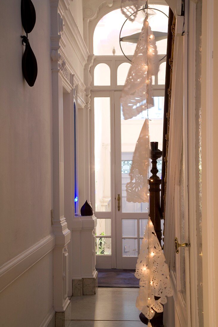 Abgehängte Lichterkette mit Papierschirmen in herrschaftlichem Treppenhaus mit Rundbogenfenster