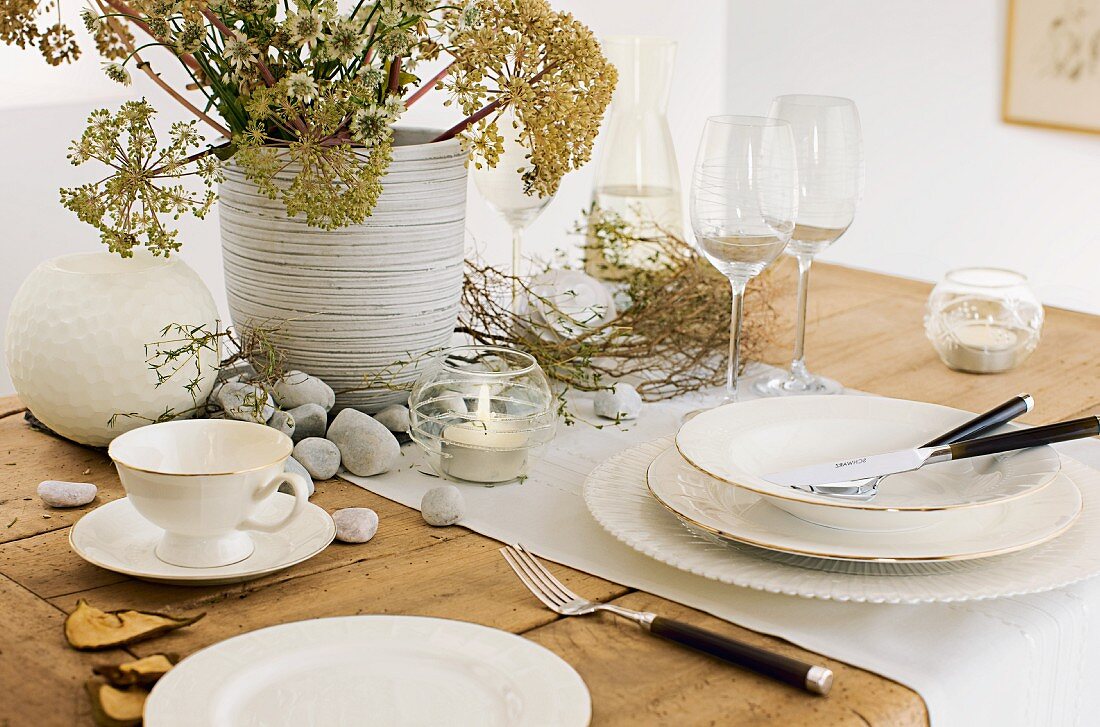 Gedeckter Tisch mit Geschirr, Gläsern und Naturmaterialien