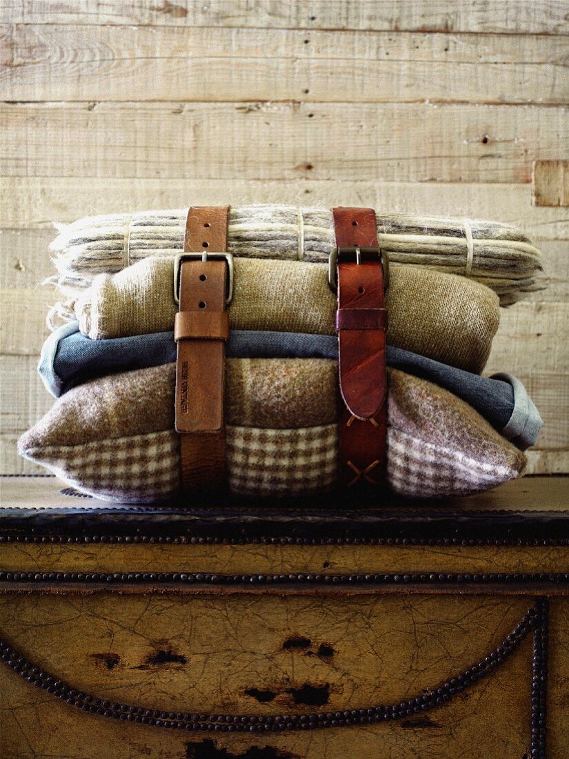 Leather belts around stack of blankets and cushions in rustic ambiance