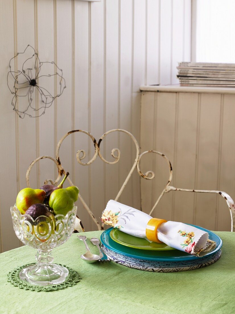 Small fruit bowl and a place setting on a table with a green tablecloth
