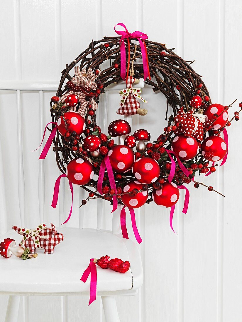 Natural grass wreath with red and white Christmas decorations on the back of a chair