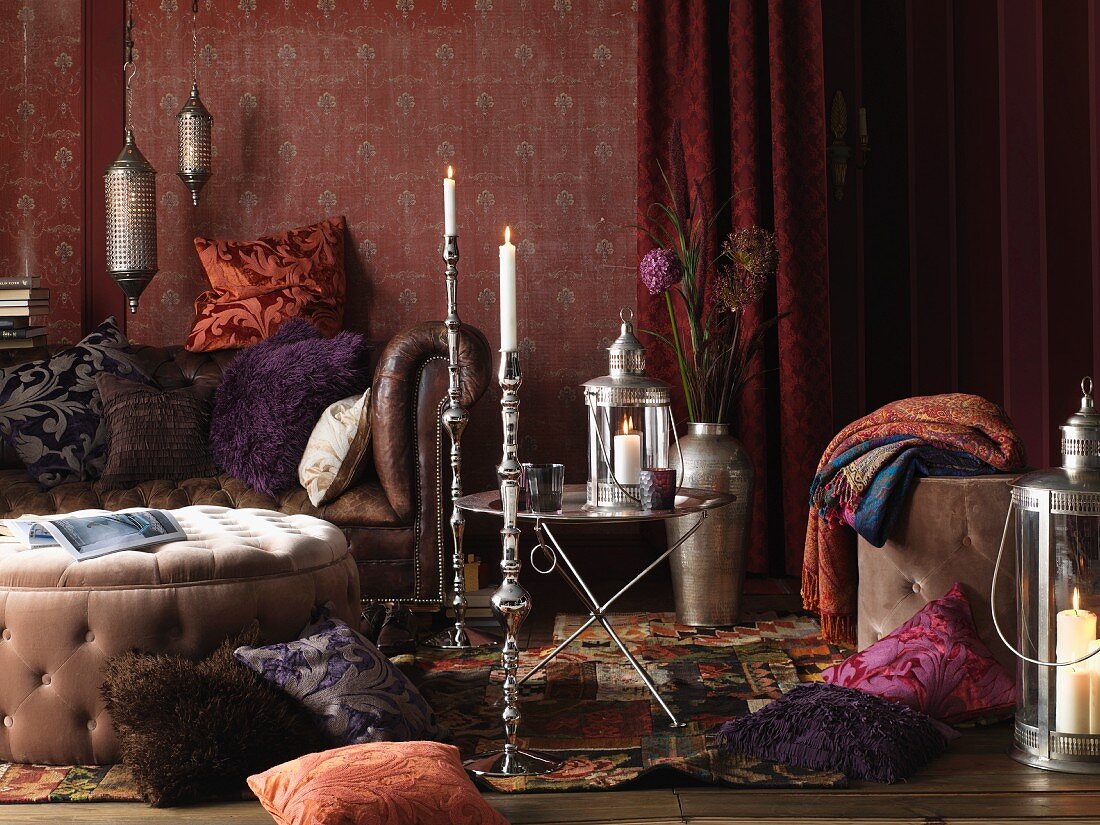 Wohnzimmer im Boheme-Look: Kissen auf Boden und auf Ledersofa, Polstertisch, Beistelltisch und silberne Kerzenständer