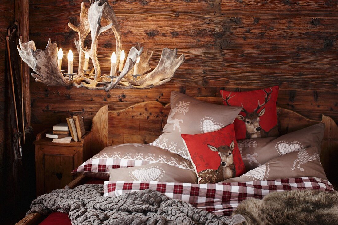 Gemütliches Schlafzimmer mit Geweih-Leuchter in einem traditionellen Chalet