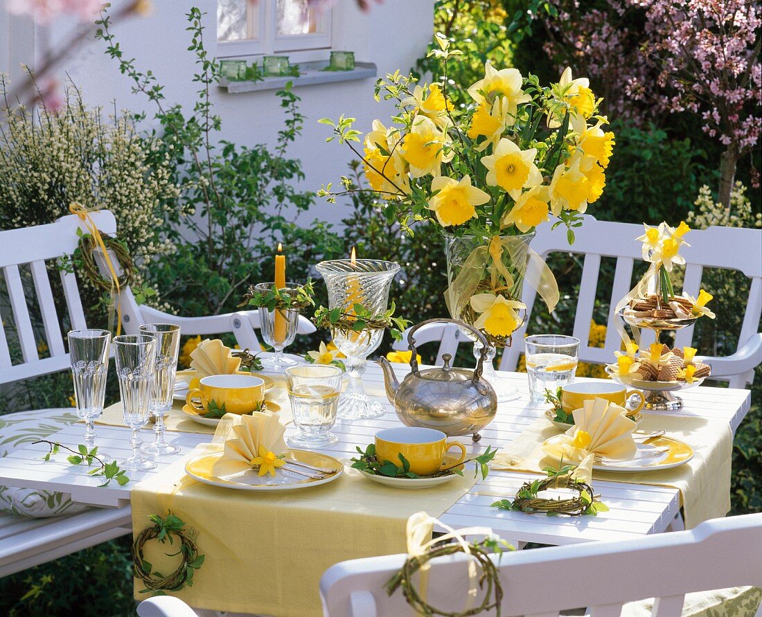 Yellow table decorations with serviettes folded into a fan shape, bouquet of narcissus and small willow wreaths