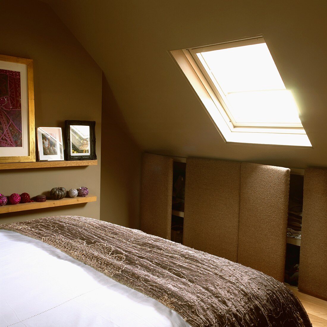 Schlafzimmer im Dachgeschoss mit grünen Wänden, stoffbezogenem Einbauschrank, Bett und Dachfenster