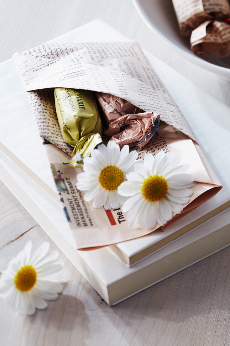 Gastgeschenk in gebastelter Tasche aus Zeitungspapier mit Bonbons & Blüten befüllt