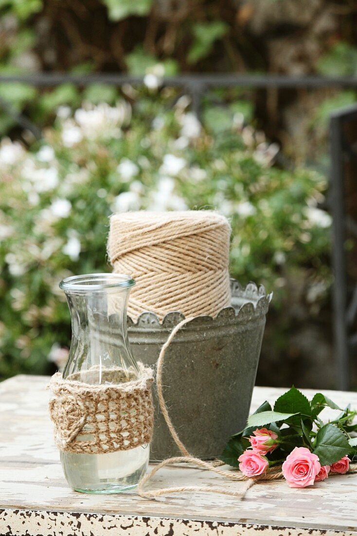 Gas bottle with hand-knitted cover and reel of yarn in metal container on garden table