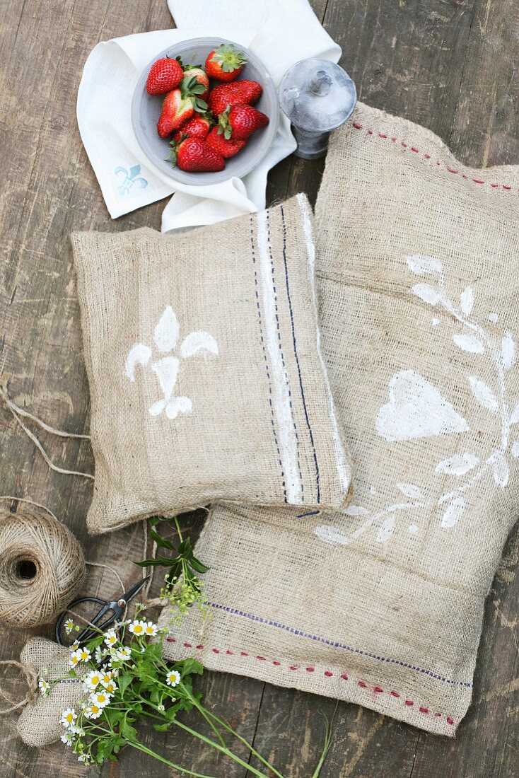 Hand-sewn hessian cushions on wooden table in garden