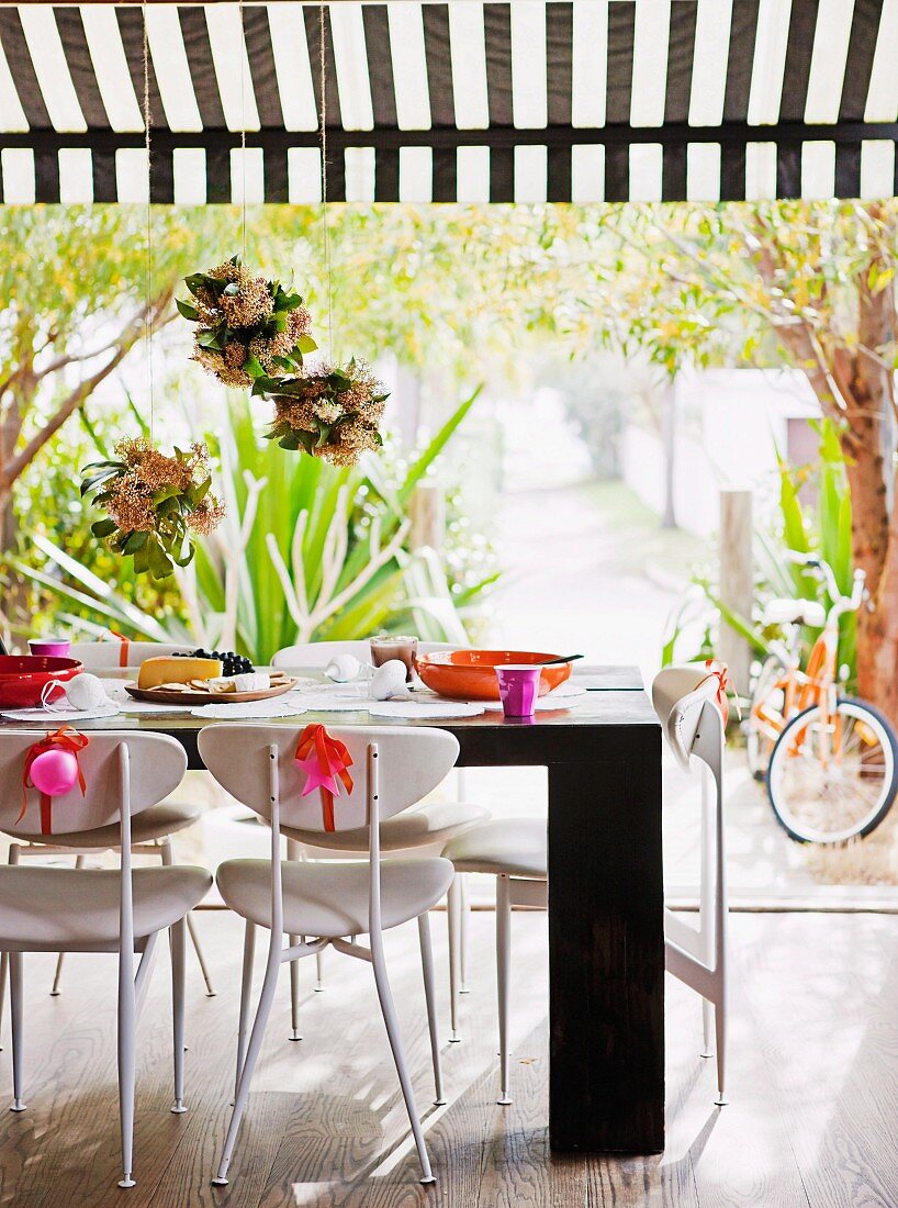 Aufgehängte Blumengestecken über festlich dekoriertem Tisch mit Stühlen