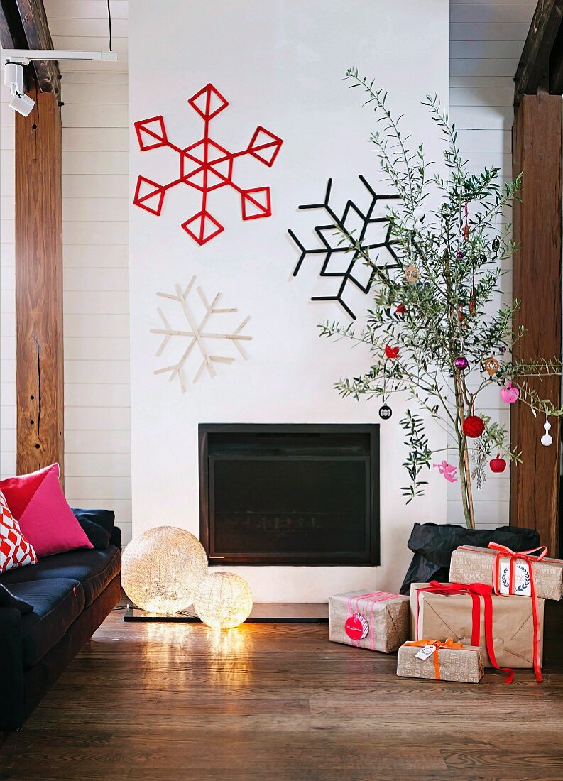 Interior with fireplace festively decorated with snowflakes on wall & wrapped Christmas presents