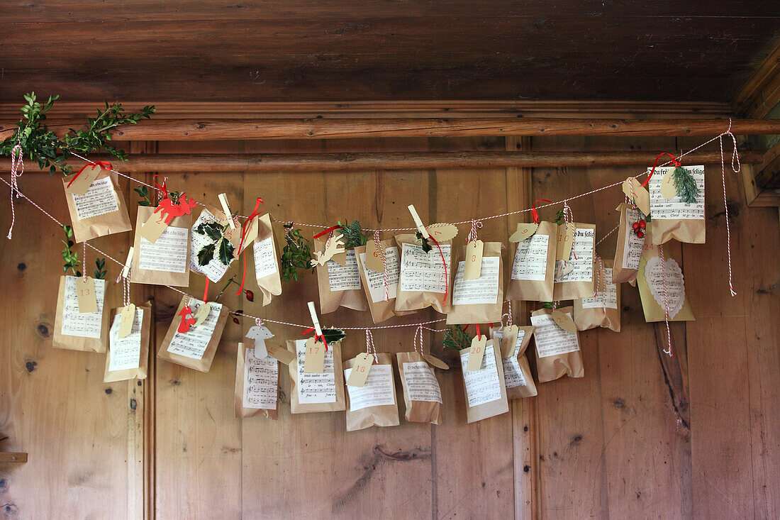 Selbstgestalteter Adventskalender - mit Notenblättern beklebte und verzierte Packpapiertüten an einer Schnur aufgehängt