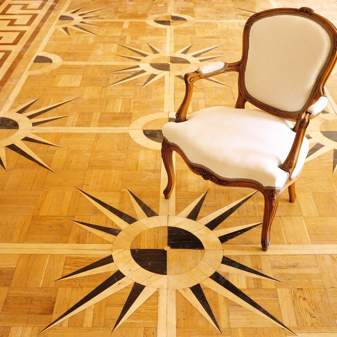 Rokoko Stuhl auf Parkettboden mit Windrosen-Motiv als Intarsie