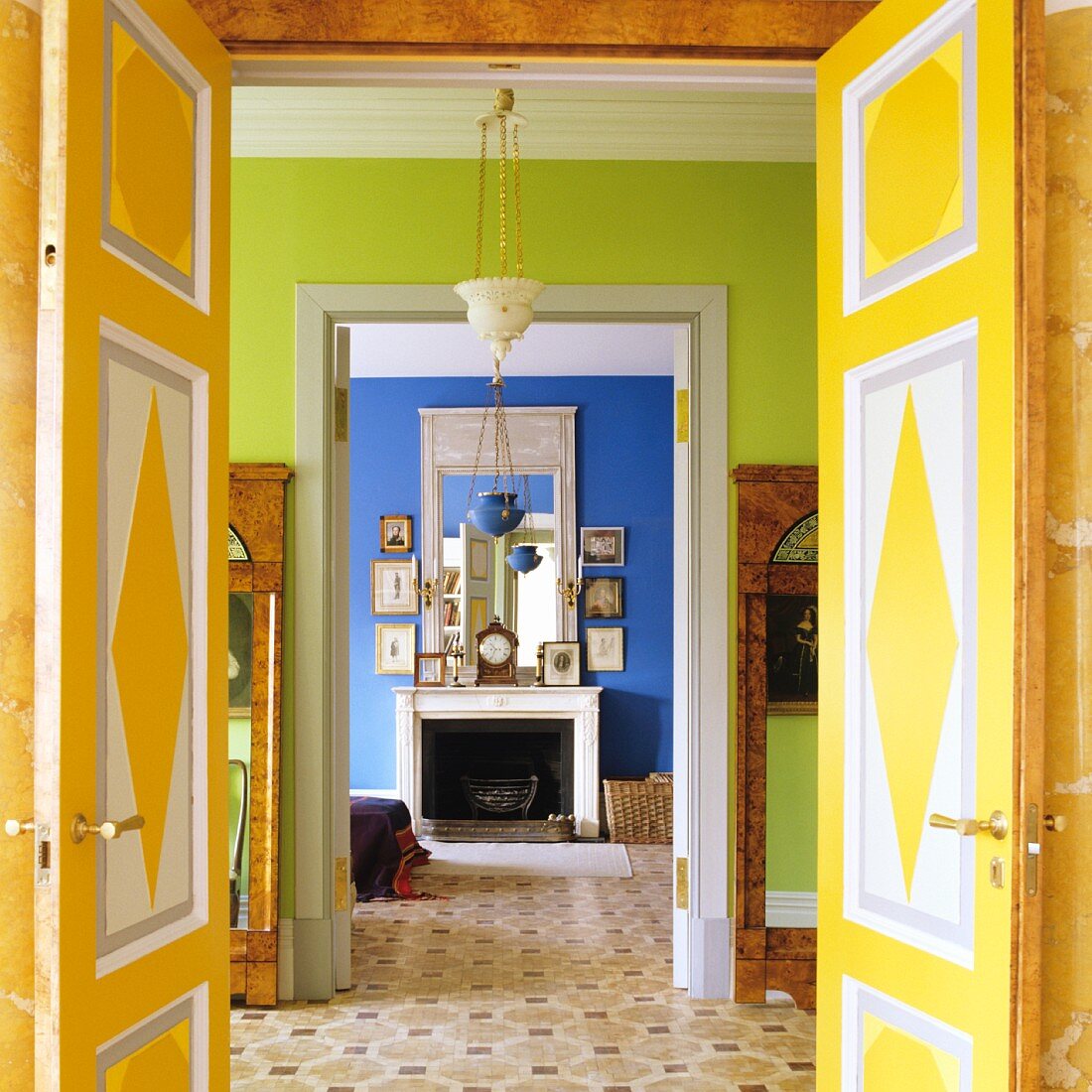 Offene Flügeltüren mit farbenfroher Bemalung und Blick durch grünen Nebenraum in blaues Zimmer mit offenem Kamin