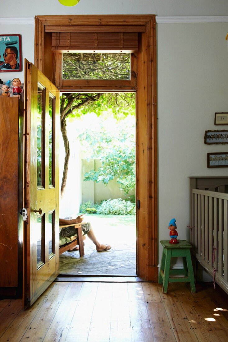 Kinderzimmer mit offener Terrassentür aus Holz und Glas mit Blick in sonnigen, begrünten Innenhof