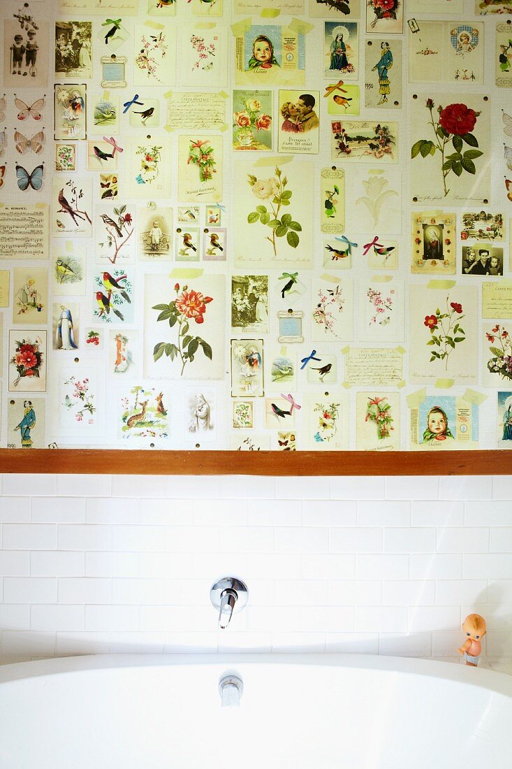 Weisses Waschbecken vor teilweise gefliester Wand, darüber Bildersammlung mit Blumen- und Tiermotiven