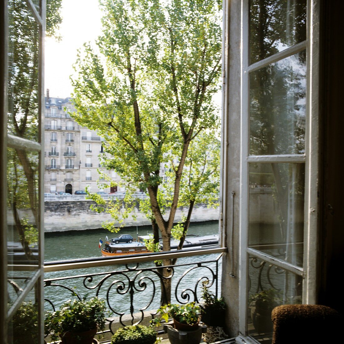 Blick auf die Seine durch offenes, französisches Fenster mit schmiedeeisernem Brüstungsgitter