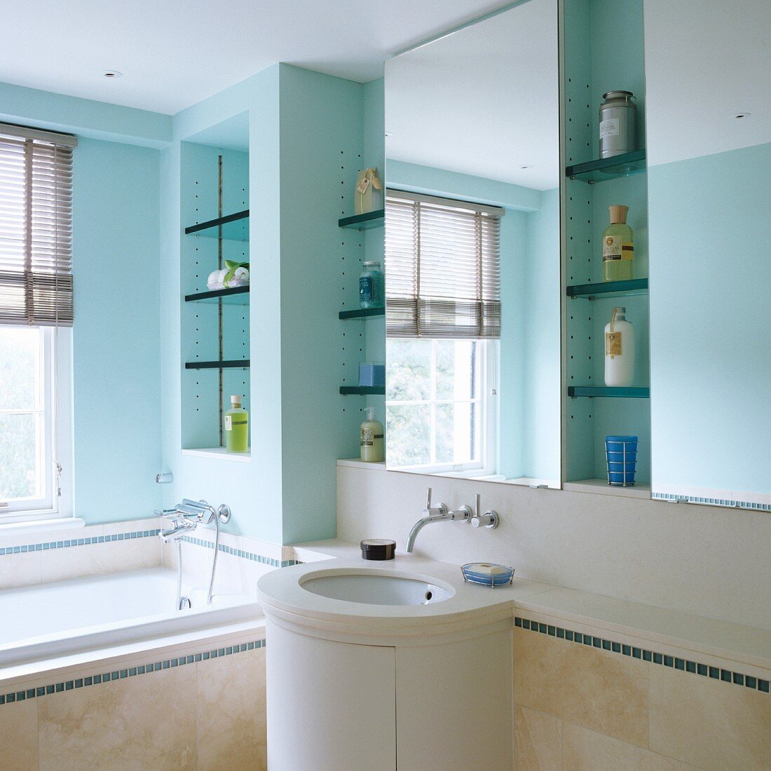 Badezimmer mit türkis getönten Wänden, Regalnischen, Spiegeln und zylinderförmiger Waschtisch
