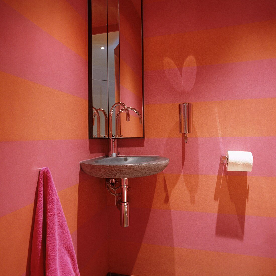 Stone corner washbasin and mirrored cabinet in pink and orange striped guest toilet