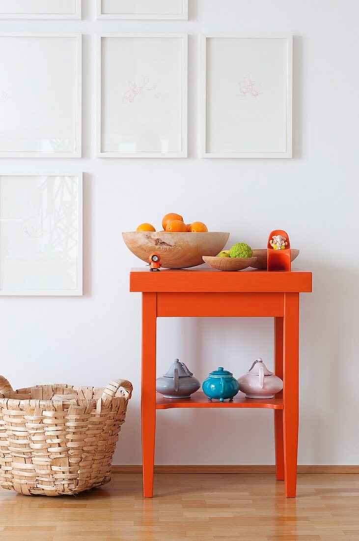 Orangefarbener Beistelltisch mit Orangen in Holzschale und Teekannen