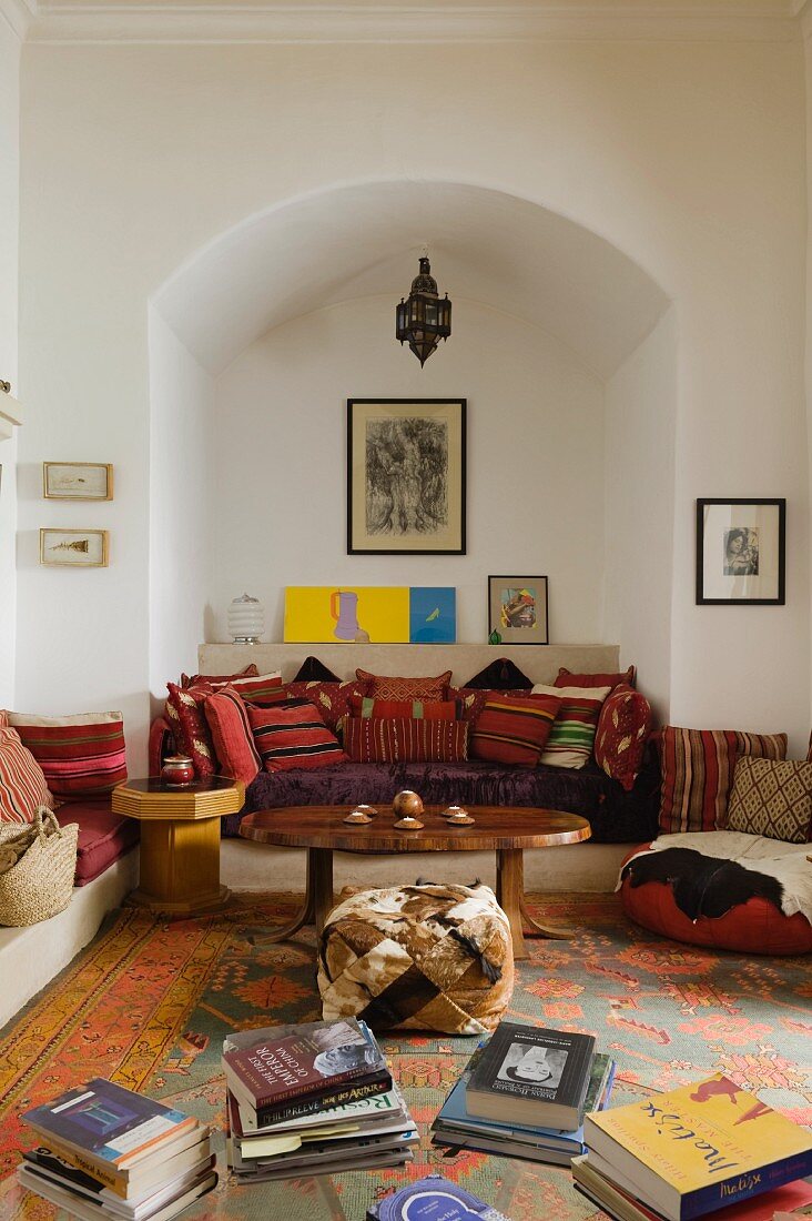 Moroccan interior with collection of scatter cushions on masonry couch in niche