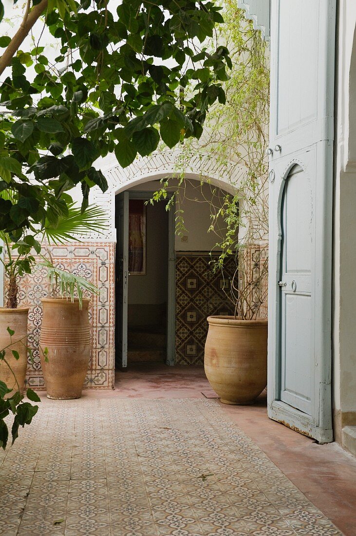 Idyllic courtyard of Moroccan house with plants in hand-made terracotta pots and mosaic tiles on floor and walls