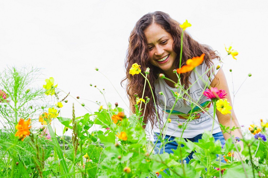 Lächelnde Frau pflückt Blumen im Garten