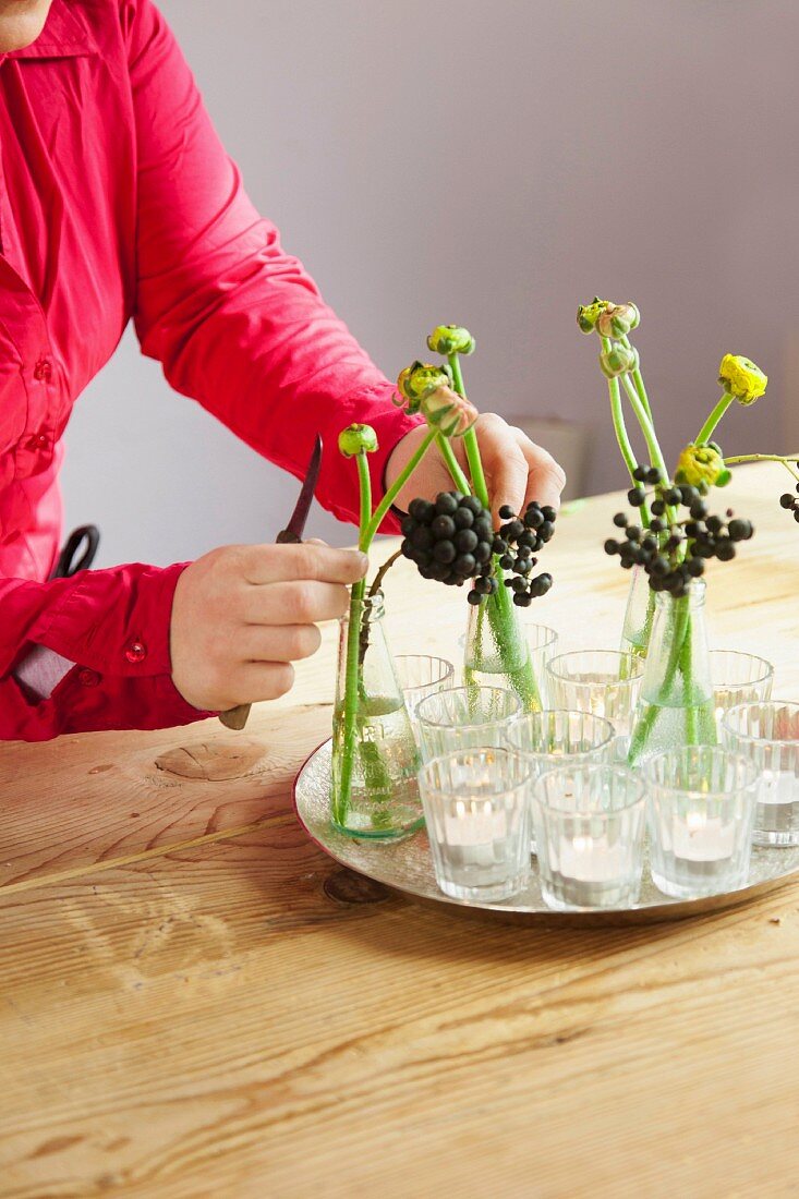 Frau bereitet kleine Blumenvasen vor