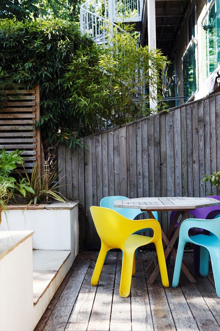 Farbige Designer-Plastikstühle auf einer geschützten Holzterrasse