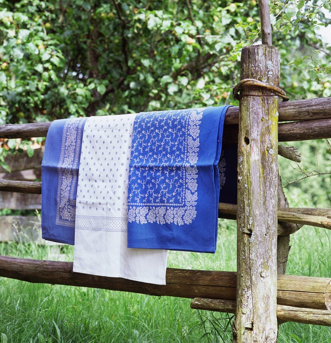 Blue and white table linen hanging over wooden fence