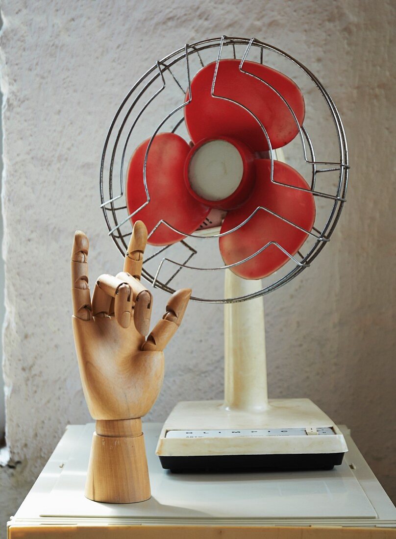 Hand of jointed doll in front of retro table fan