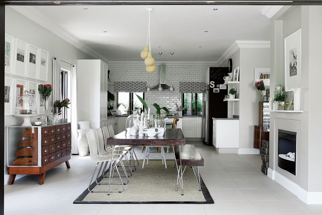 Open-plan interior with dining area in front of fireplace and adjoining fitted kitchen