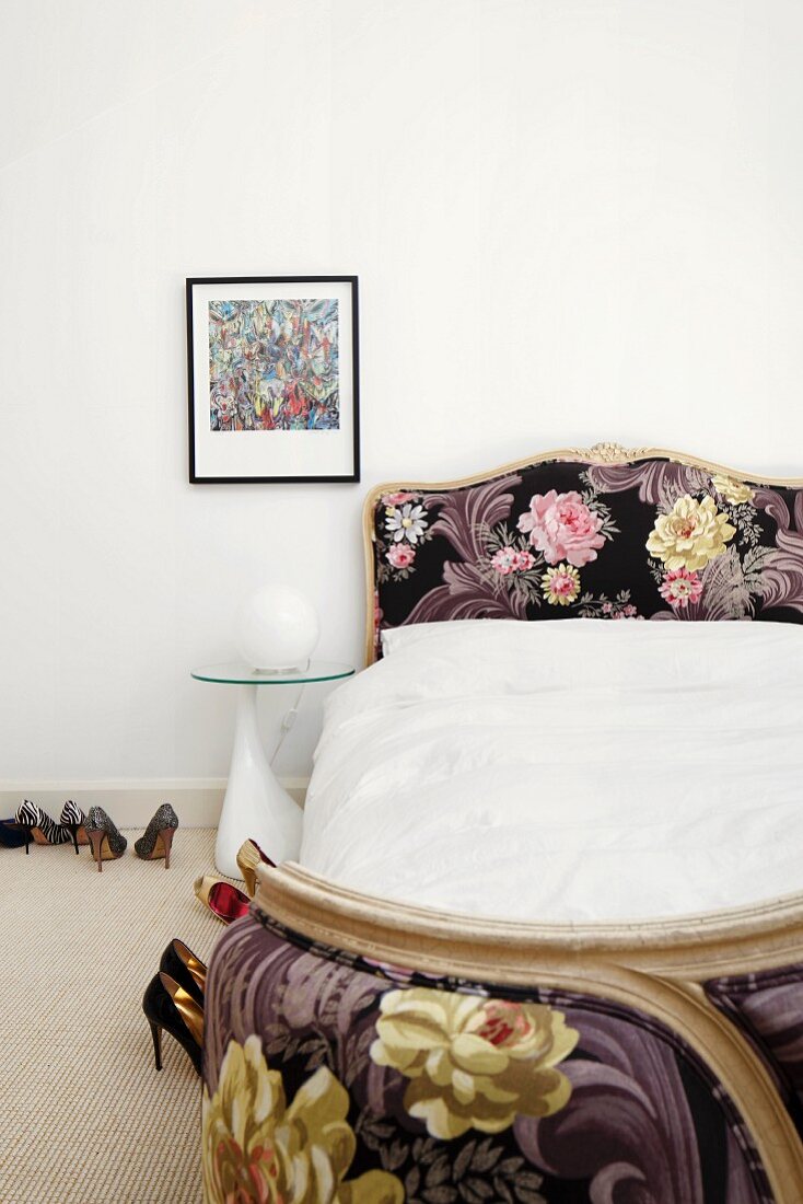 Antikes, französisches Corbeille-Bett mit neuer, floral gemusterter Polsterung, daneben Nachttisch mit Glasplatte