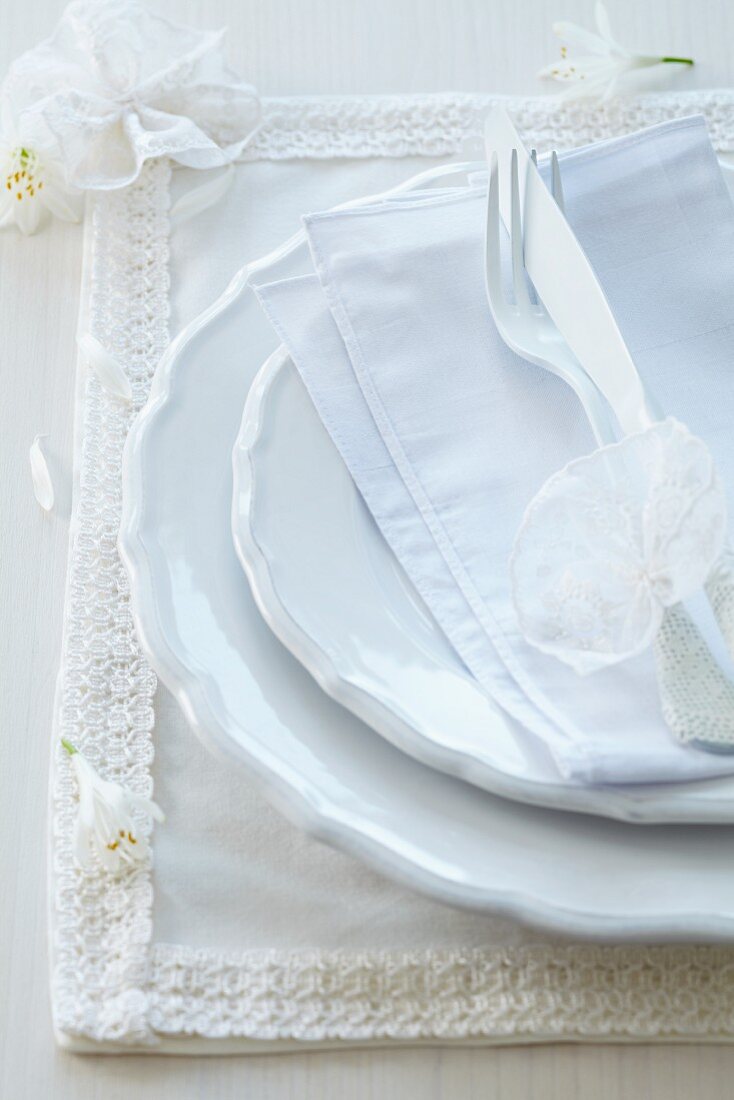 Romantic place setting with fabric place mat decorated with ribbon and lace flowers
