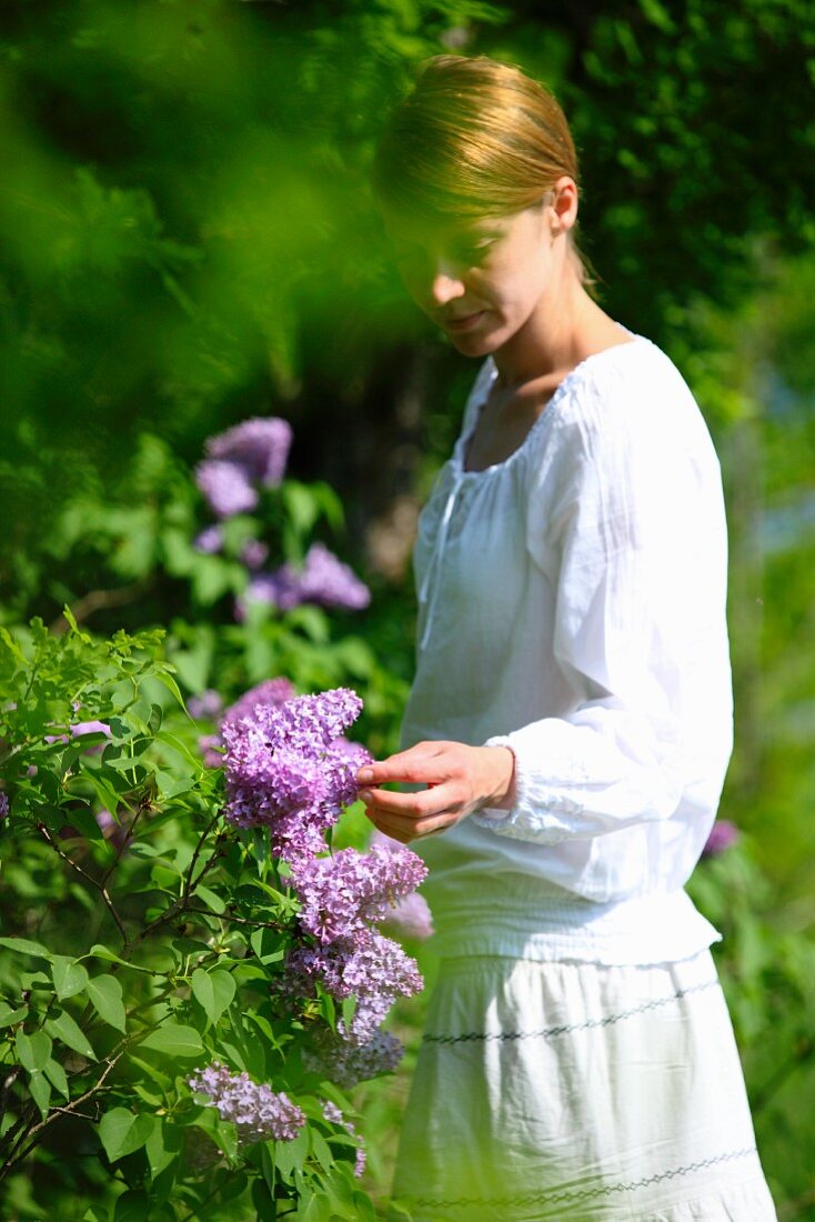 A young woman looking at the flowering lilac