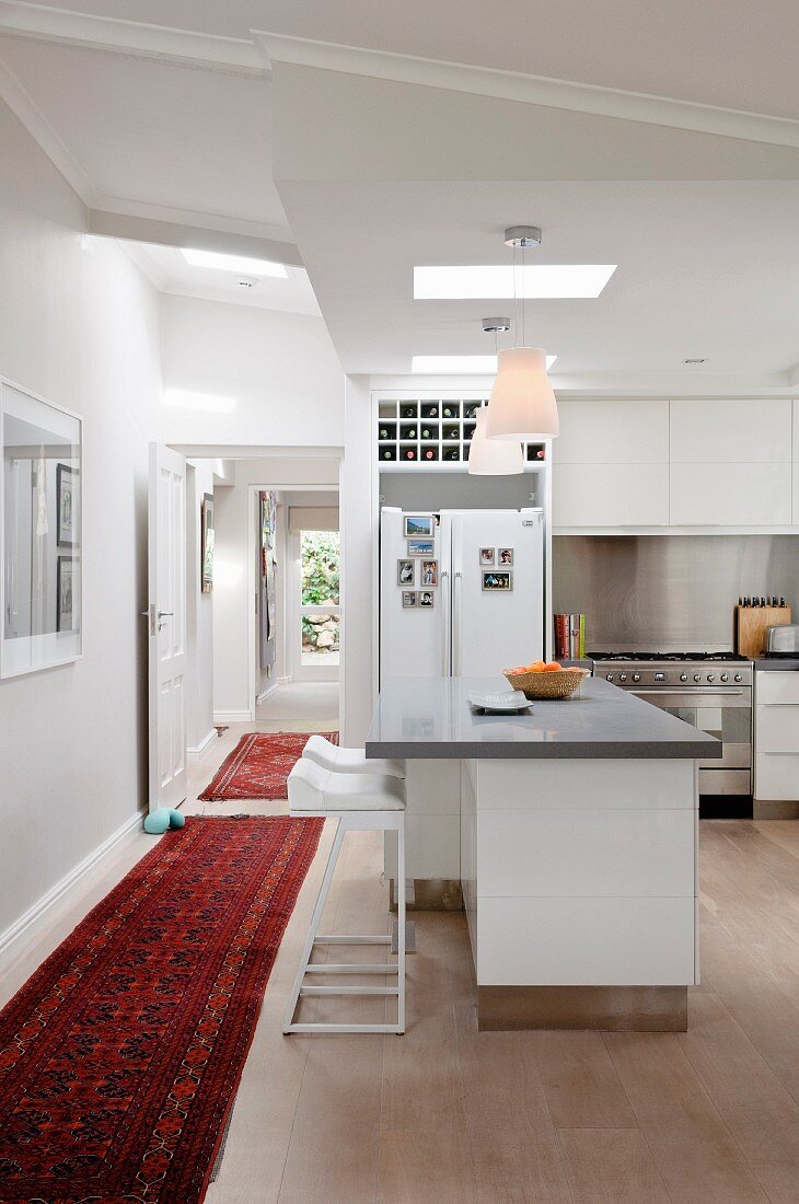 Zeitgenössische offene weiße Küche mit orientalischem Teppichläufer im Gangbereich