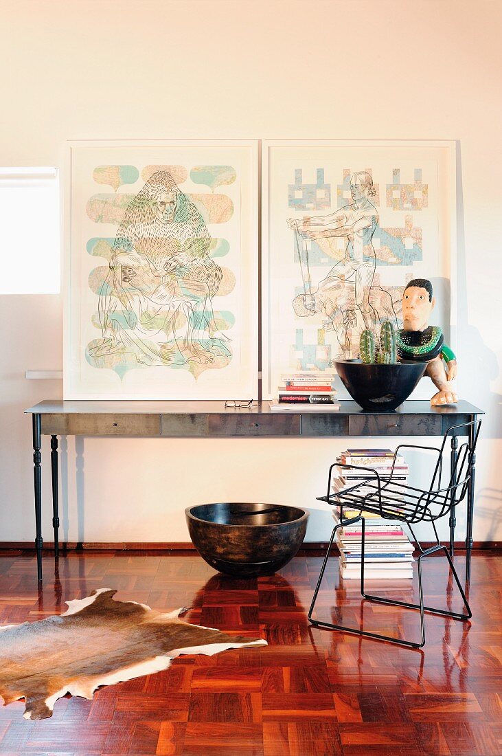 Pictures on postmodern console table behind metal chair on old mosaic parquet floor