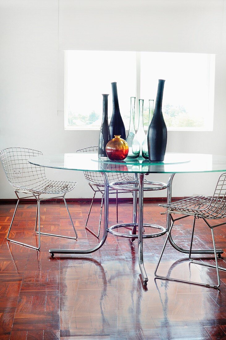 Vasensammlung auf Glastisch und Bauhaus Metallgitterstühle in minimalistischem Ambiente