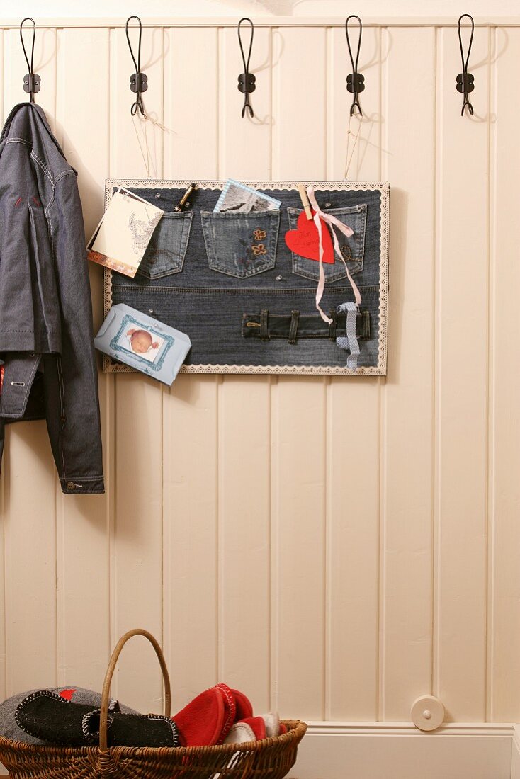 Hand-sewn, wall-mounted, denim pinboard on white-painted, wood-clad wall in hallway
