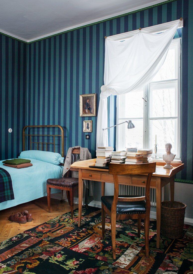 Blue striped wallpaper and Biedermeier desk below window in guest room with single bed
