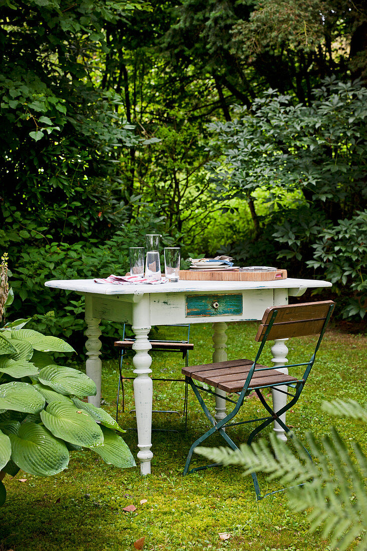 Klappbare Gartenstühle und weiss lackierter Tisch mit gedrechselten Beinen im Shabby Stil im Garten