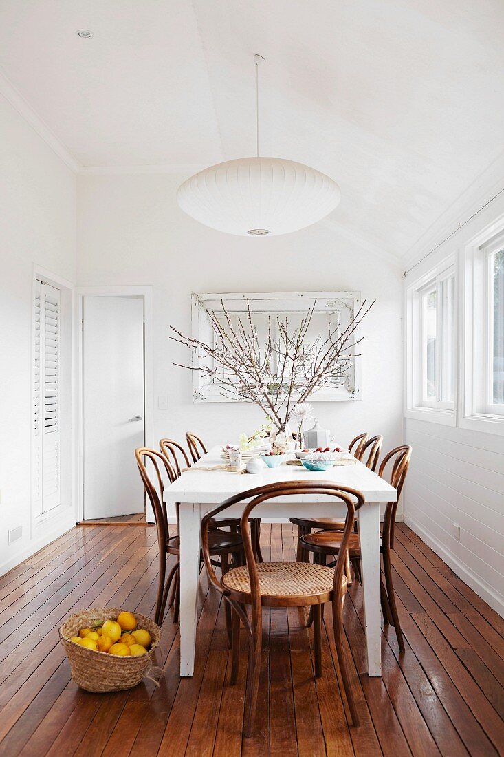 White table and Thonet chairs on elegant wooden floor in white, minimalist dining room