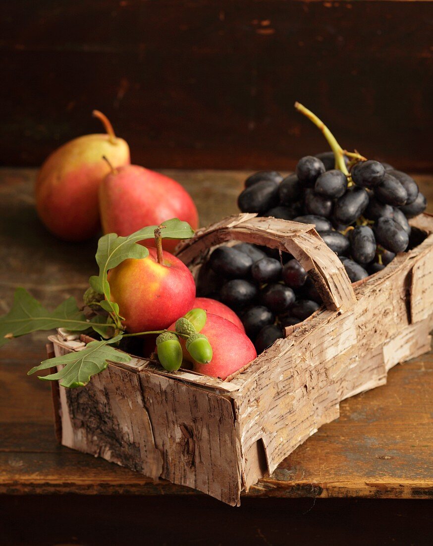Spankorb mit Birkenrinde umwickelt, gefüllt mit Birnen und Weintrauben