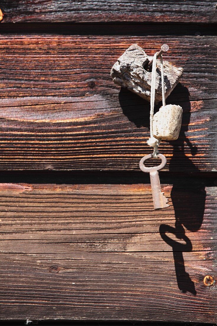 Boot key attached to cork float hanging from nail in wall of rustic wooden beams