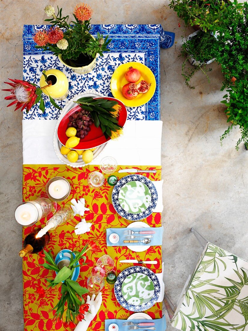 Farbenfrohe Stimmung auf dem Tisch - Blick von oben auf bunte Gedecke und tropische Blumen in Vasen
