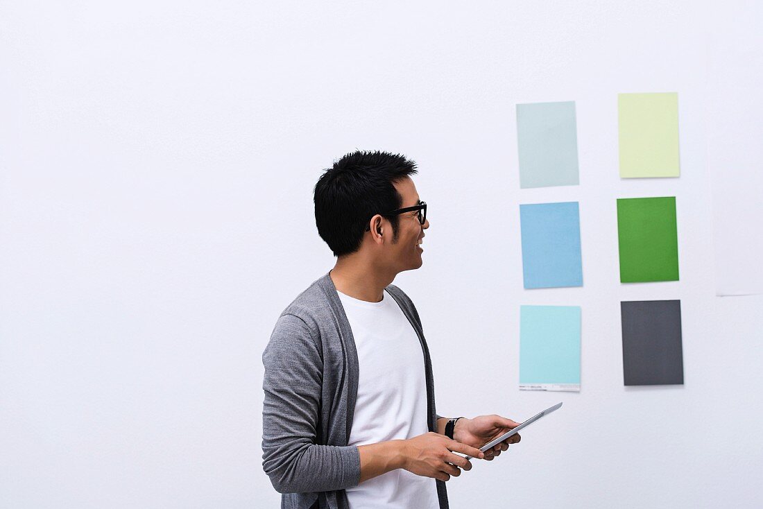Mann steht vor Wand mit verschiedenen Farbkarten